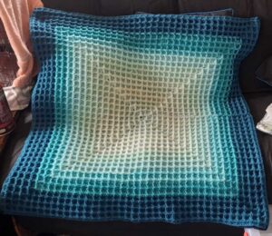 Square piece of crochet with shades of blue