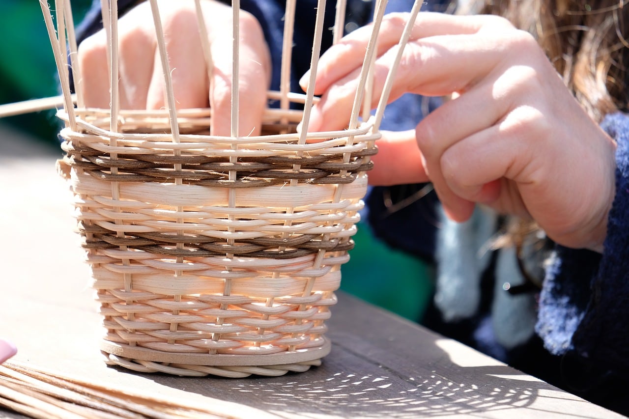 2 hands weaving a small basket